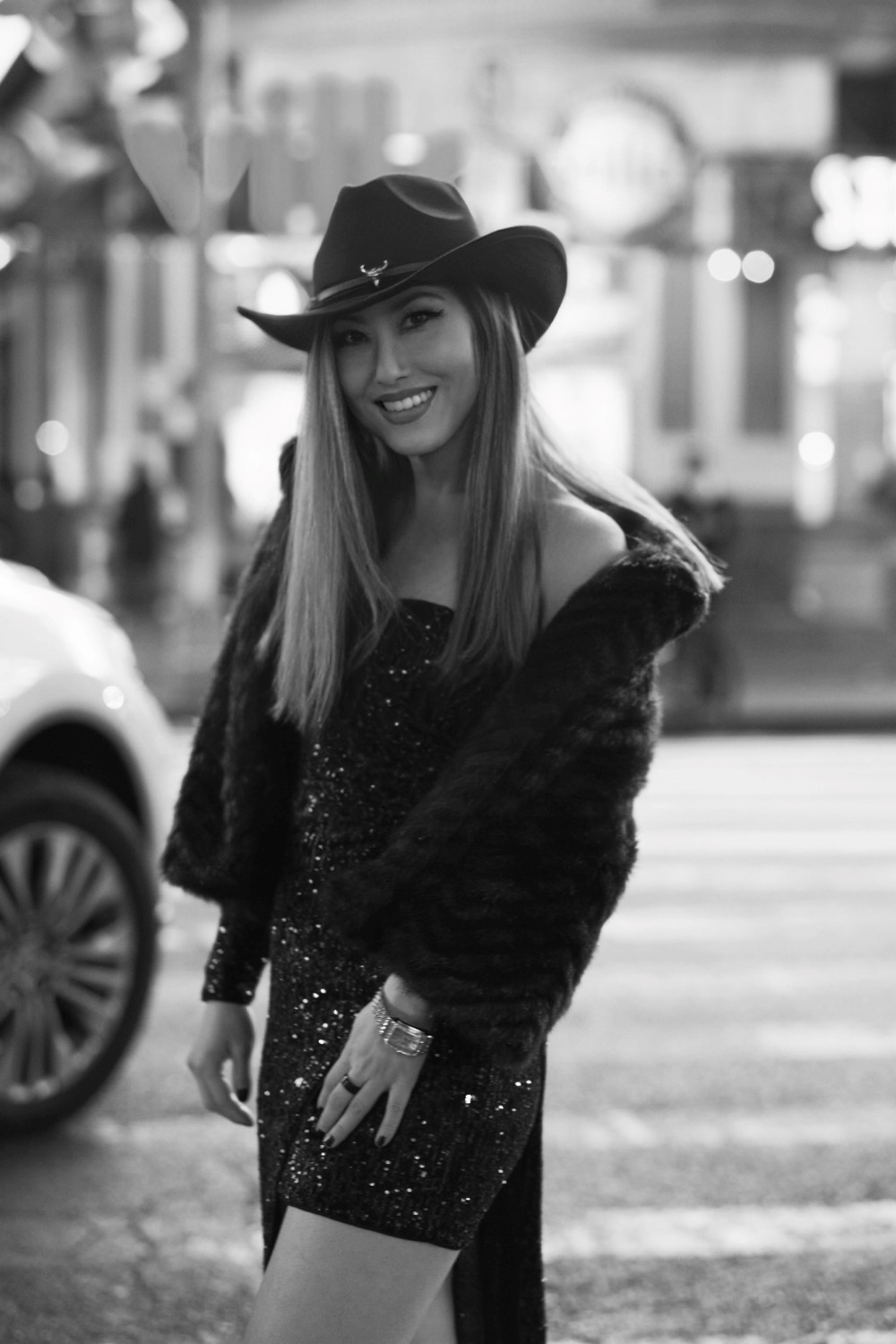 Yoko J. Bian in a cowboy hat on a city street at night
